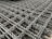 A detailed close-up of an intricate metal mesh structure with interwoven, wavy metallic strands. The metal appears to have a weathered texture with hints of rust.