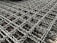 A detailed close-up of an intricate metal mesh structure with interwoven, wavy metallic strands. The metal appears to have a weathered texture with hints of rust.