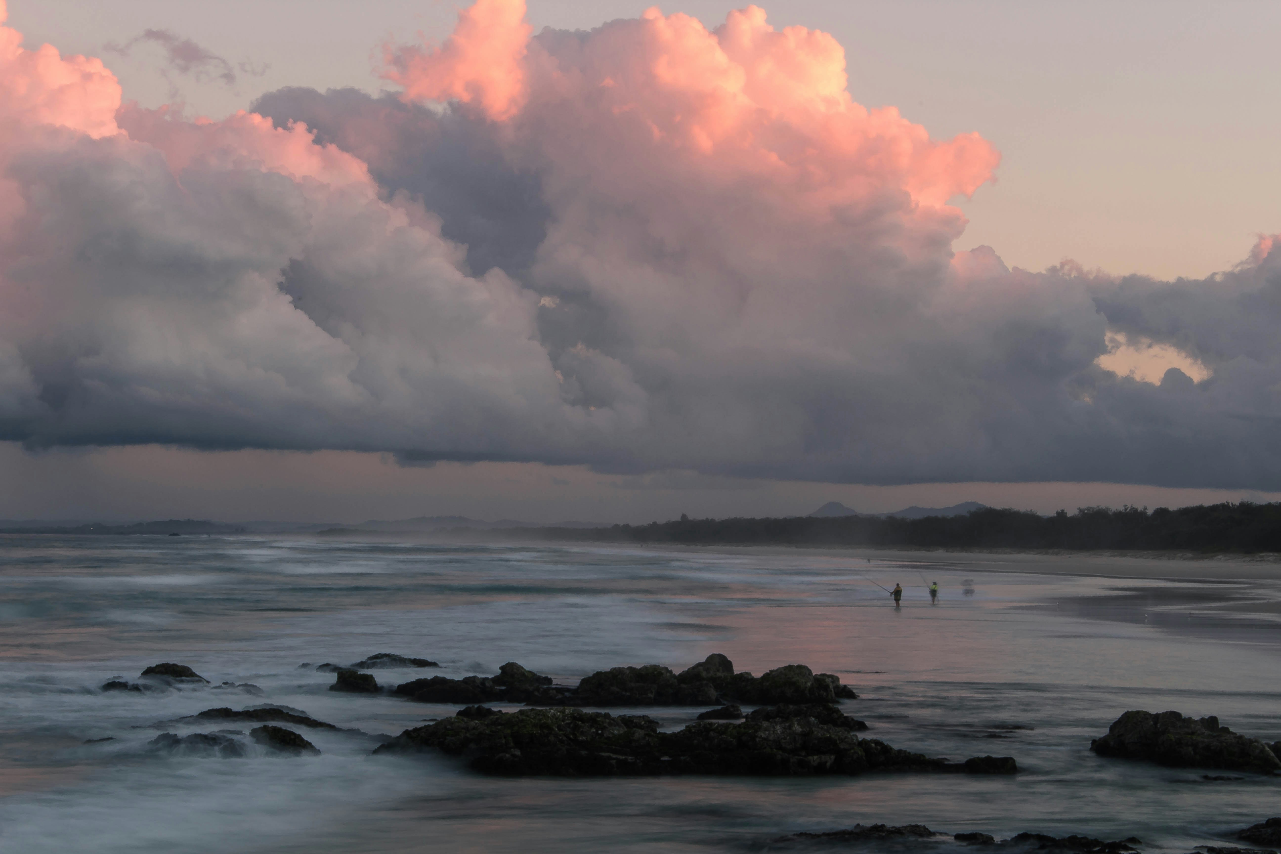 a body of water with rocks and a cloudy sky above