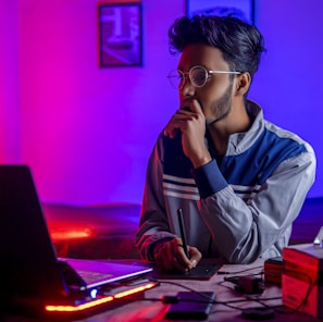 a person sitting at a desk with a laptop and a computer