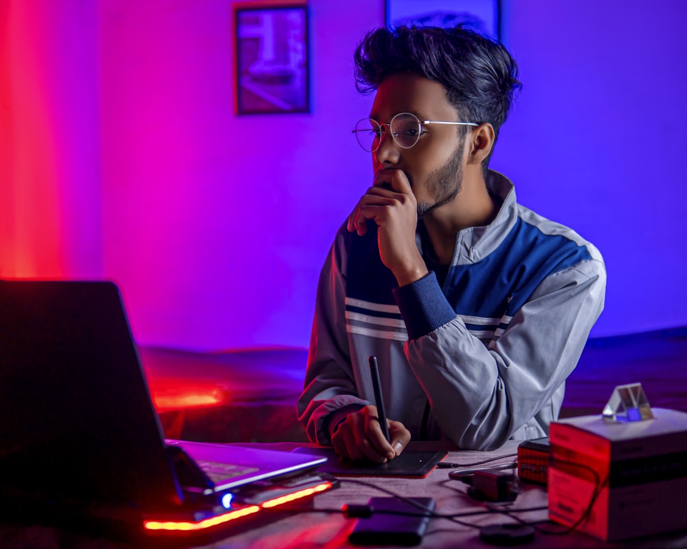 a person sitting at a desk with a laptop and a computer