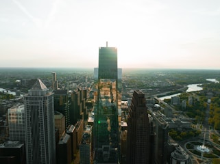 A panoramic view of the bustling Guangzhou skyline at sunset, with warm red and gold hues reflecting off the Pearl River.