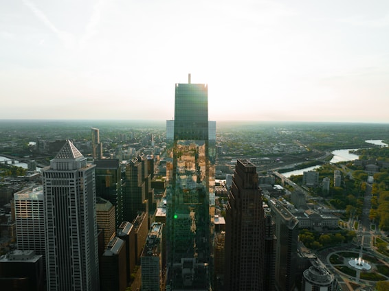 A panoramic view of the bustling Guangzhou skyline at sunset, with warm red and gold hues reflecting off the Pearl River.