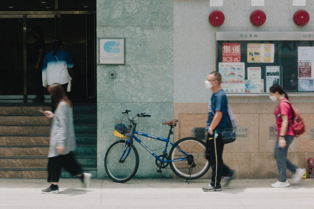 a group of people walking down a sidewalk next to a building