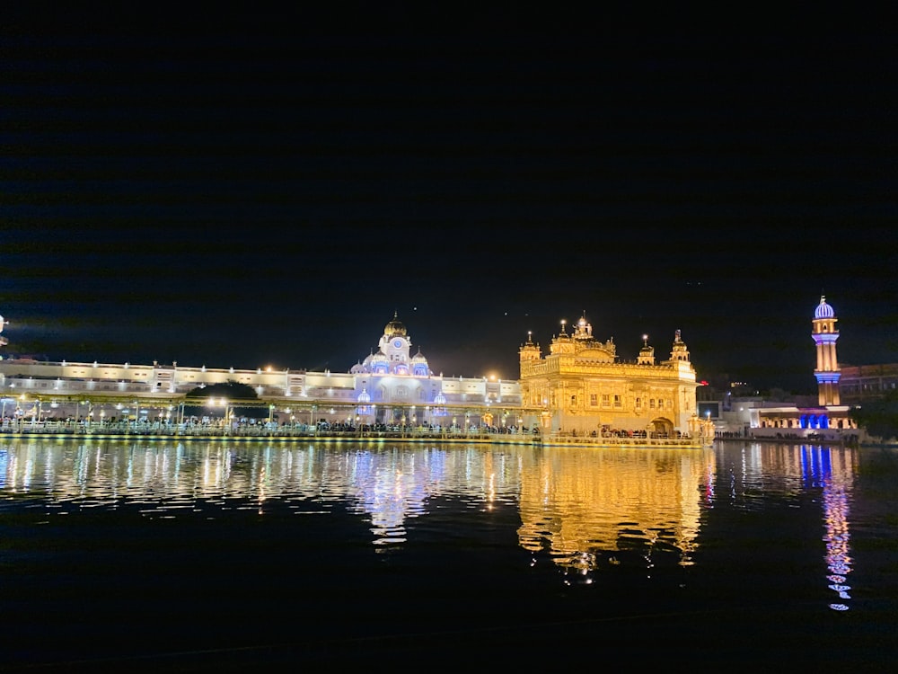 un cuerpo de agua con edificios a lo largo de él con Harmandir Sahib en el fondo