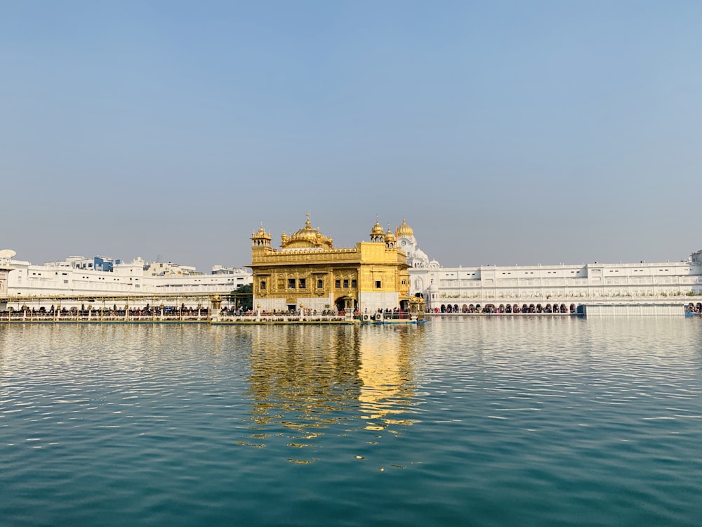 un cuerpo de agua con edificios a lo largo de él con Harmandir Sahib en el fondo