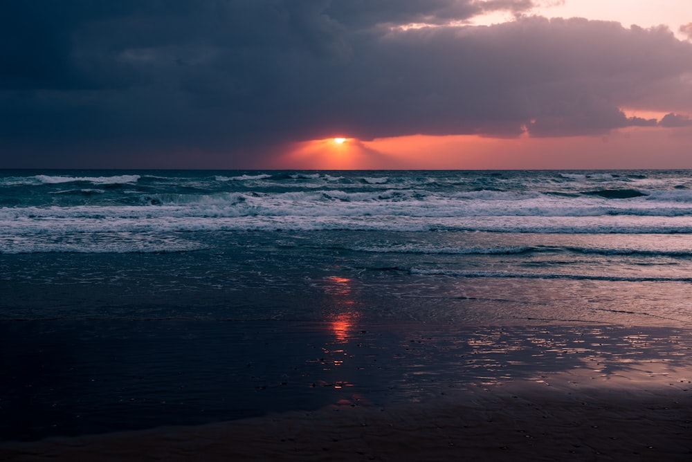 a beach with waves and a sunset