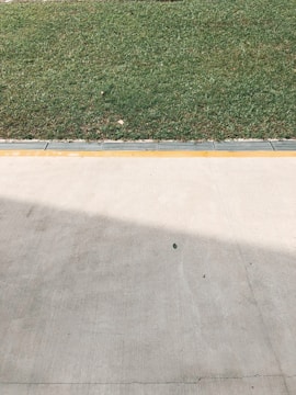 a concrete area with grass and a fence
