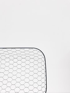 Close-up of woven wire mesh being inspected in a bright factory setting.