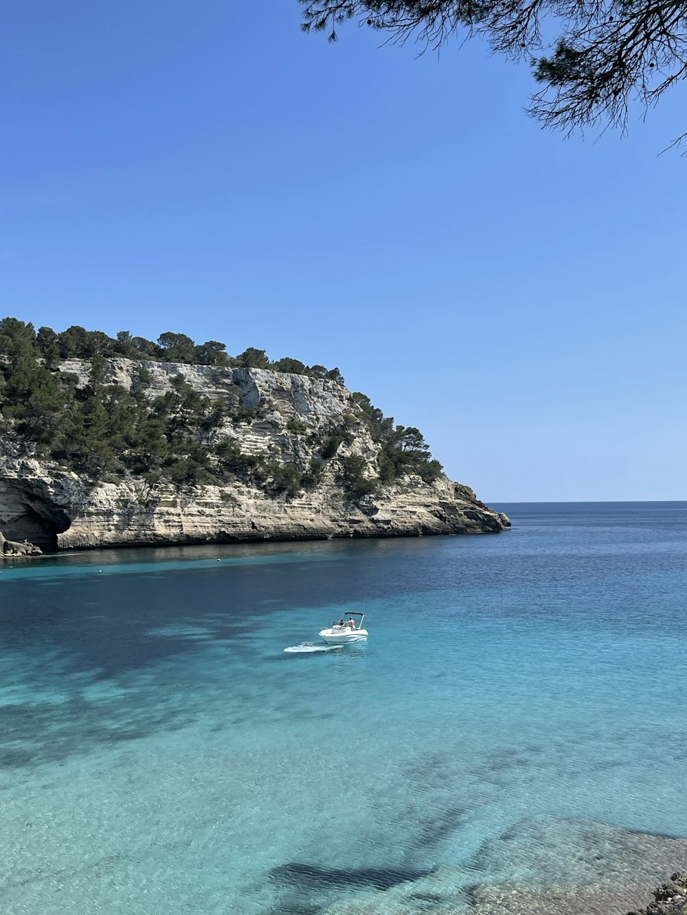 a boat in the water by a rocky island