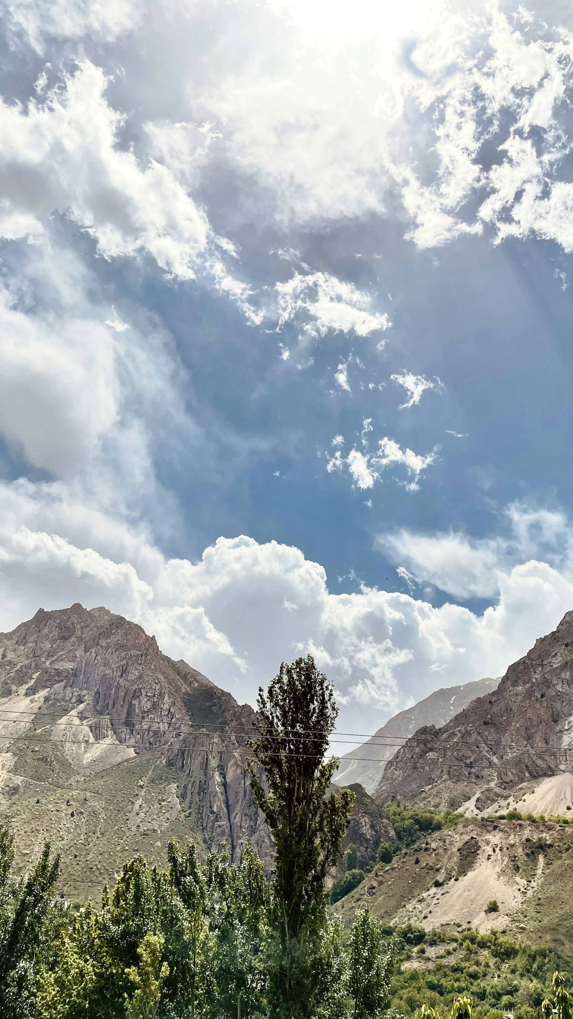 A vibrant mountain landscape with lush greenery and a clear blue sky, inviting adventure.