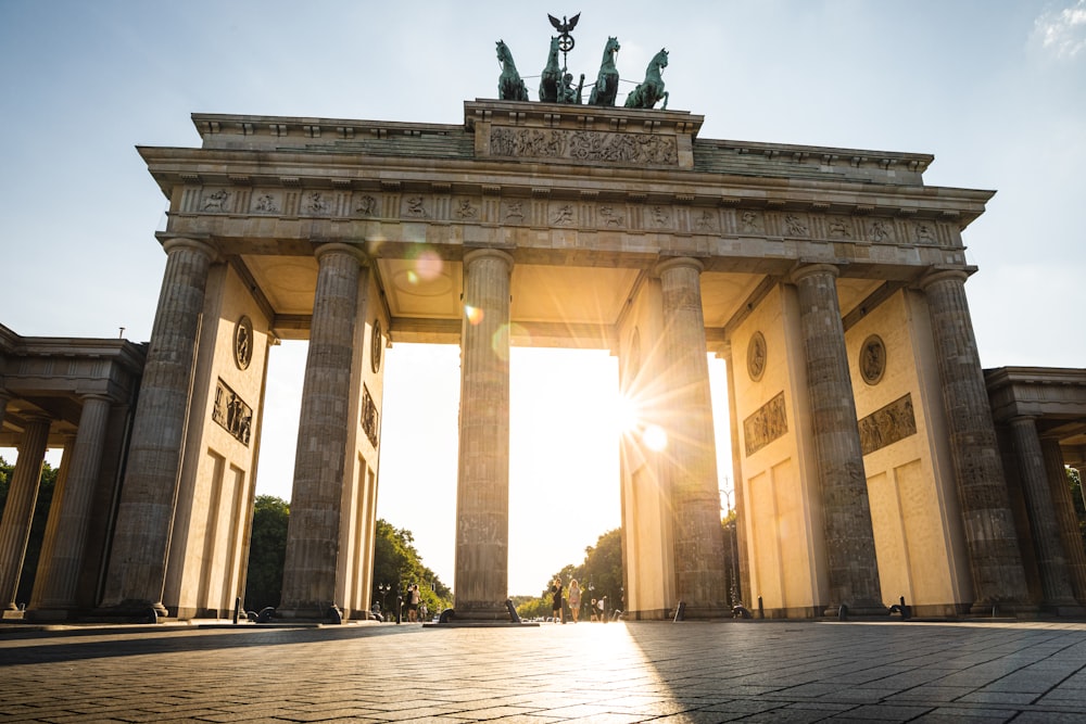 a large stone building with columns and statues on top with Brandenburg Gate in the background