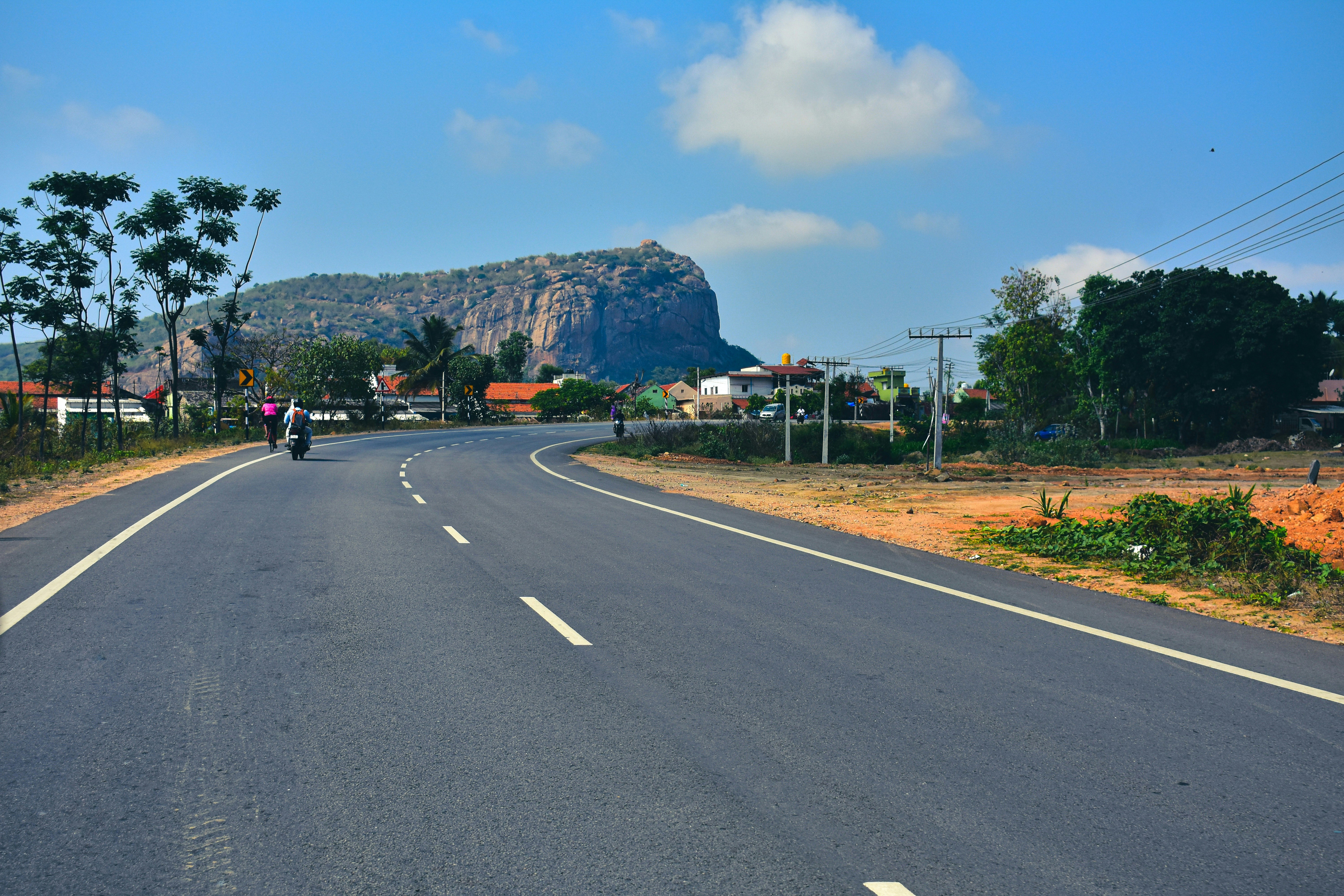 a person riding a motorcycle on a road with trees and mountains in the background