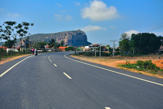 a person riding a motorcycle on a road with trees and mountains in the background