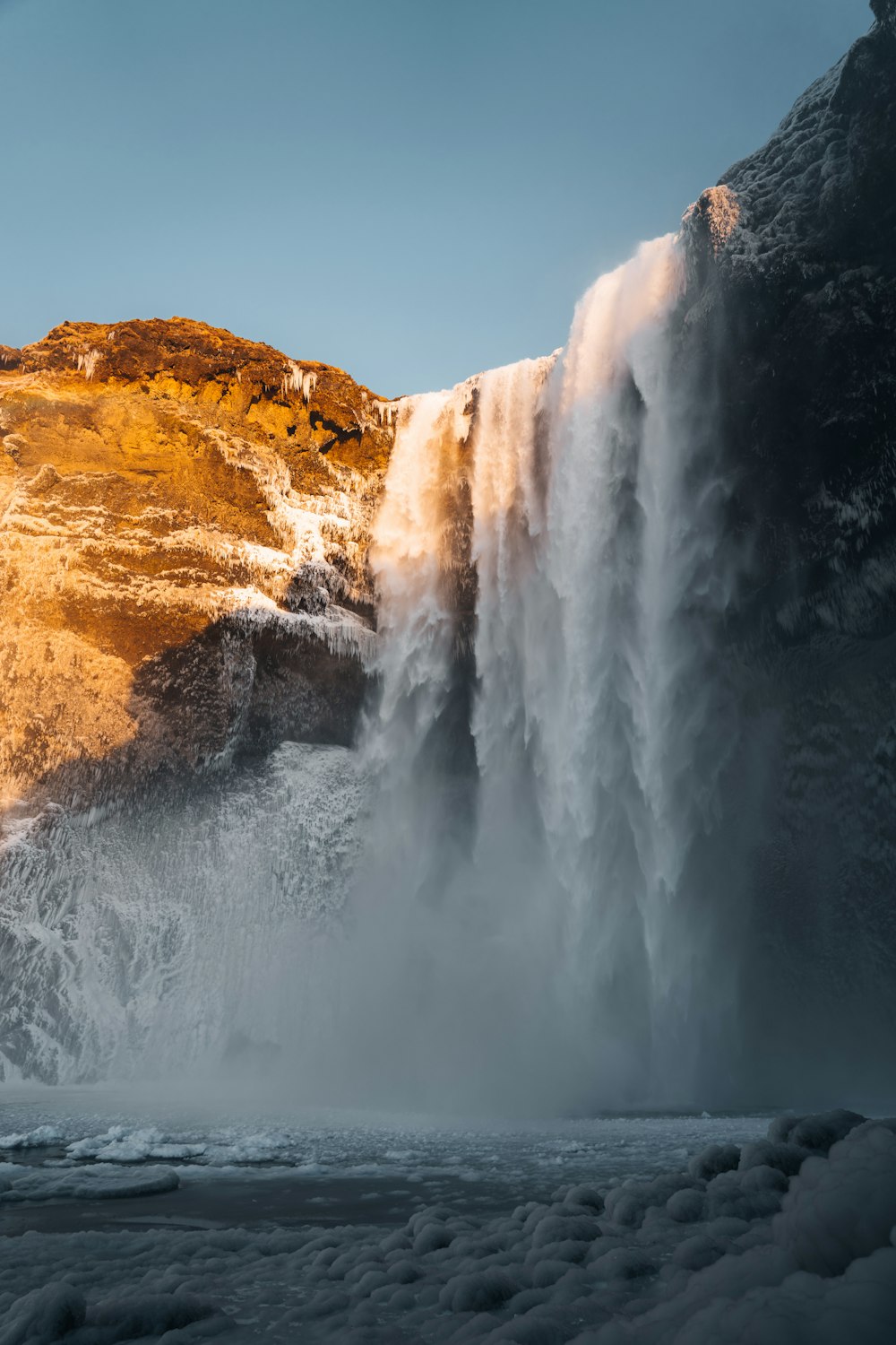 a large waterfall over a snow covered mountain