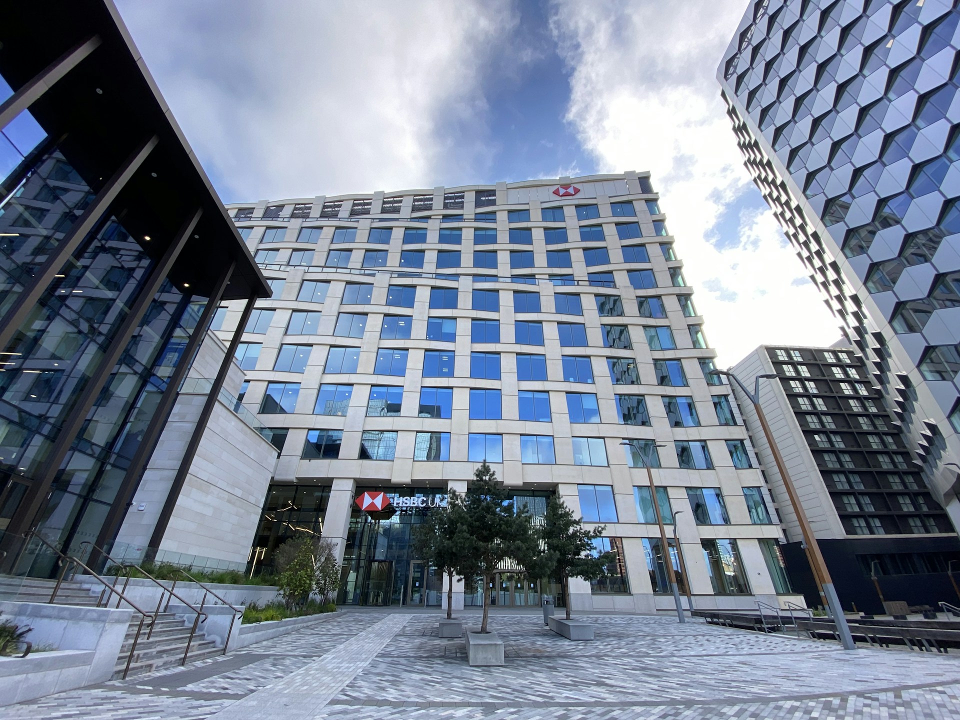 Close-up of hands exchanging keys in front of a modern office building, representing the completion of a real estate exchange.