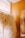 A rack filled with white bridal dresses, hanging neatly in a wooden-furnished room. There is a floor-to-ceiling mirror on the right side reflecting the dresses and part of the golden rod the gowns hang on.