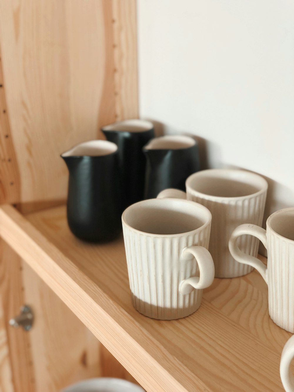 a group of coffee cups on a wooden shelf