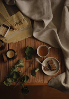 A serene morning scene with a cup of herbal tea, herbalcow balm, and a cow ghee jar on a wooden table.