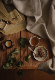 A rustic wooden table displaying jars of golden honey, colorful spice blends, and steaming cups of tea.