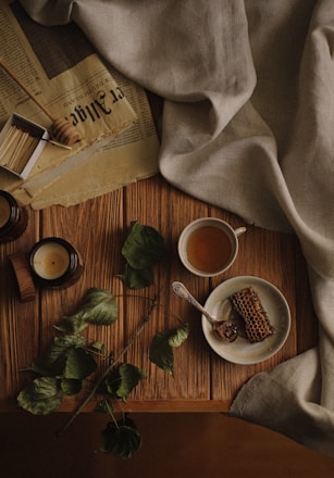 A rustic wooden table displaying jars of golden honey, colorful spice blends, and steaming cups of tea.
