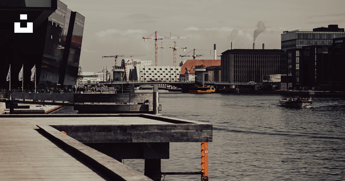 Foto Un Muelle Con Un Barco En El Agua Por Edificios Imagen foto-un-muelle-con-un-barco-en-el-agua-por-edificios-imagen