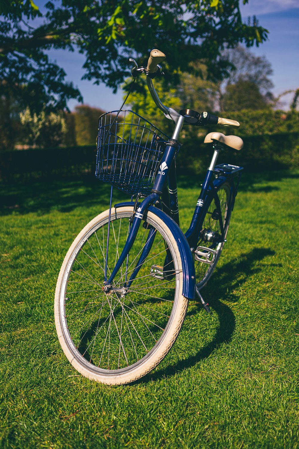 a bicycle with a basket on the front parked in a grassy area