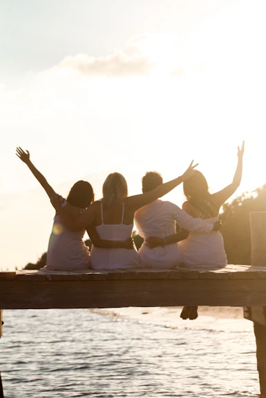 a group of people sitting on a dock with their hands up