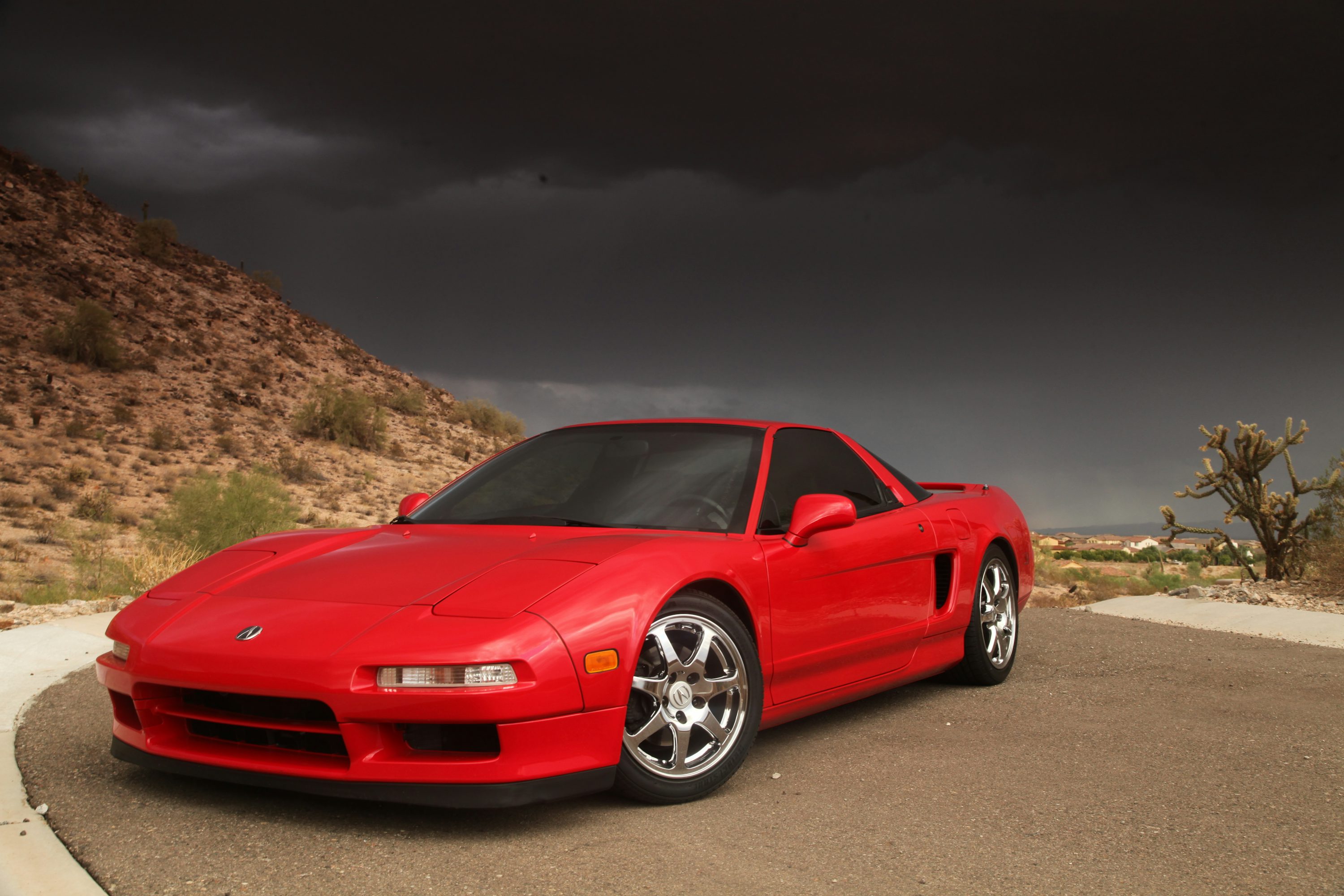 a red sports car parked on a road with hills in the background