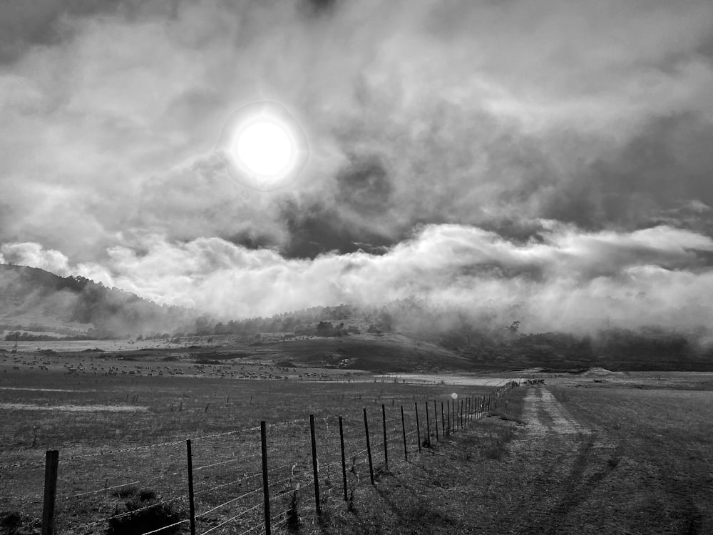 a fenced off field with a cloudy sky above