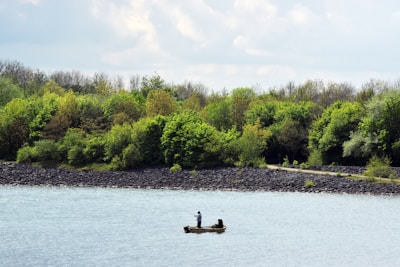 Family enjoying fishing from a boat on calm waters surrounded by lush trees.