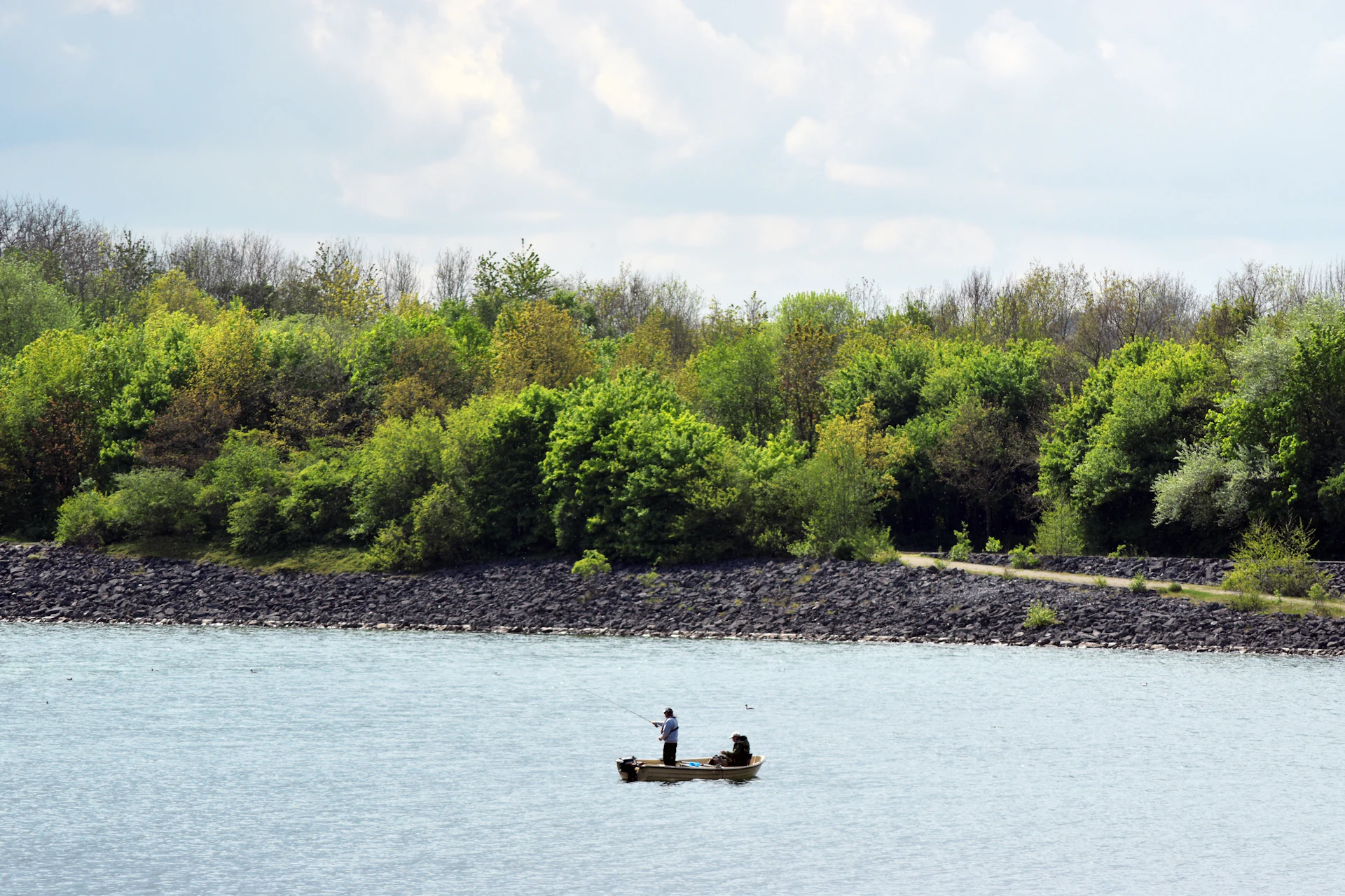 A serene fishing scene at dawn in Belitung, with a small boat drifting on calm waters surrounded by lush greenery.