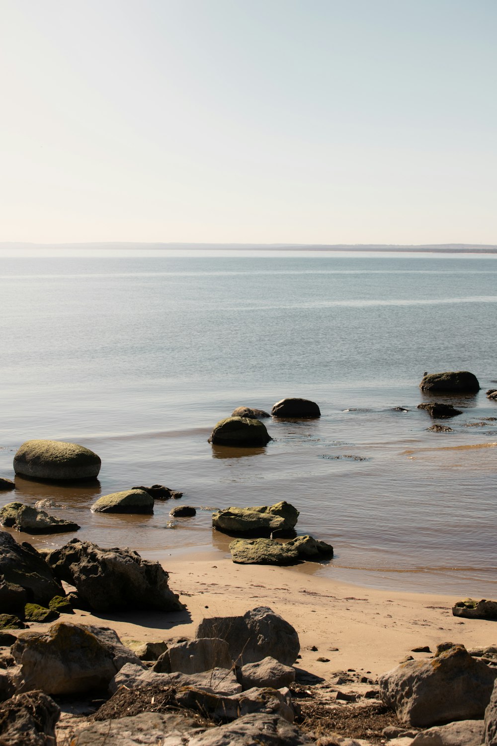 a rocky beach with a body of water in the background