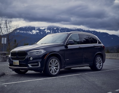 A sturdy black SUV parked in front of a mountain backdrop.