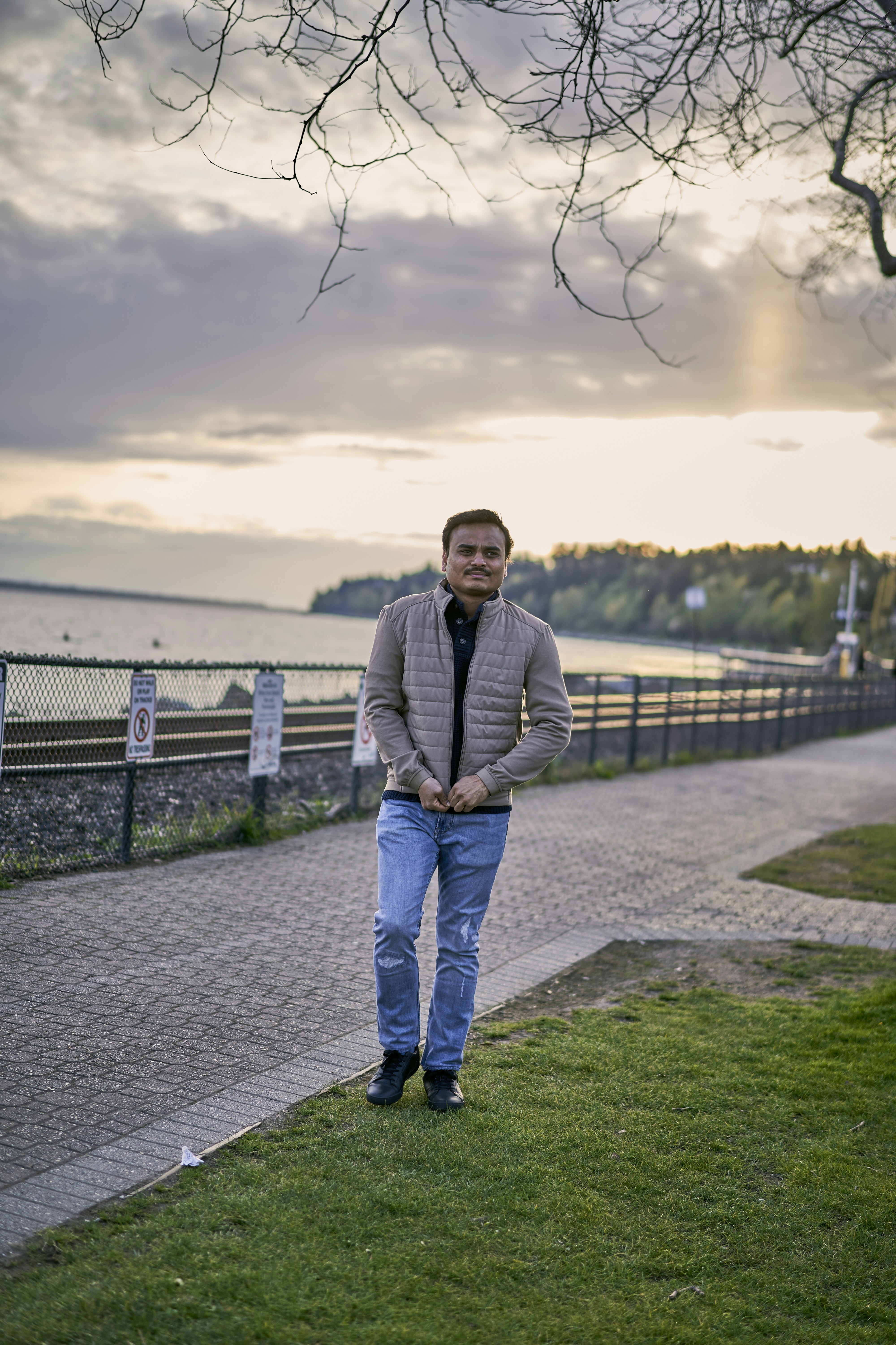 a person standing on a path by a fence and a body of water