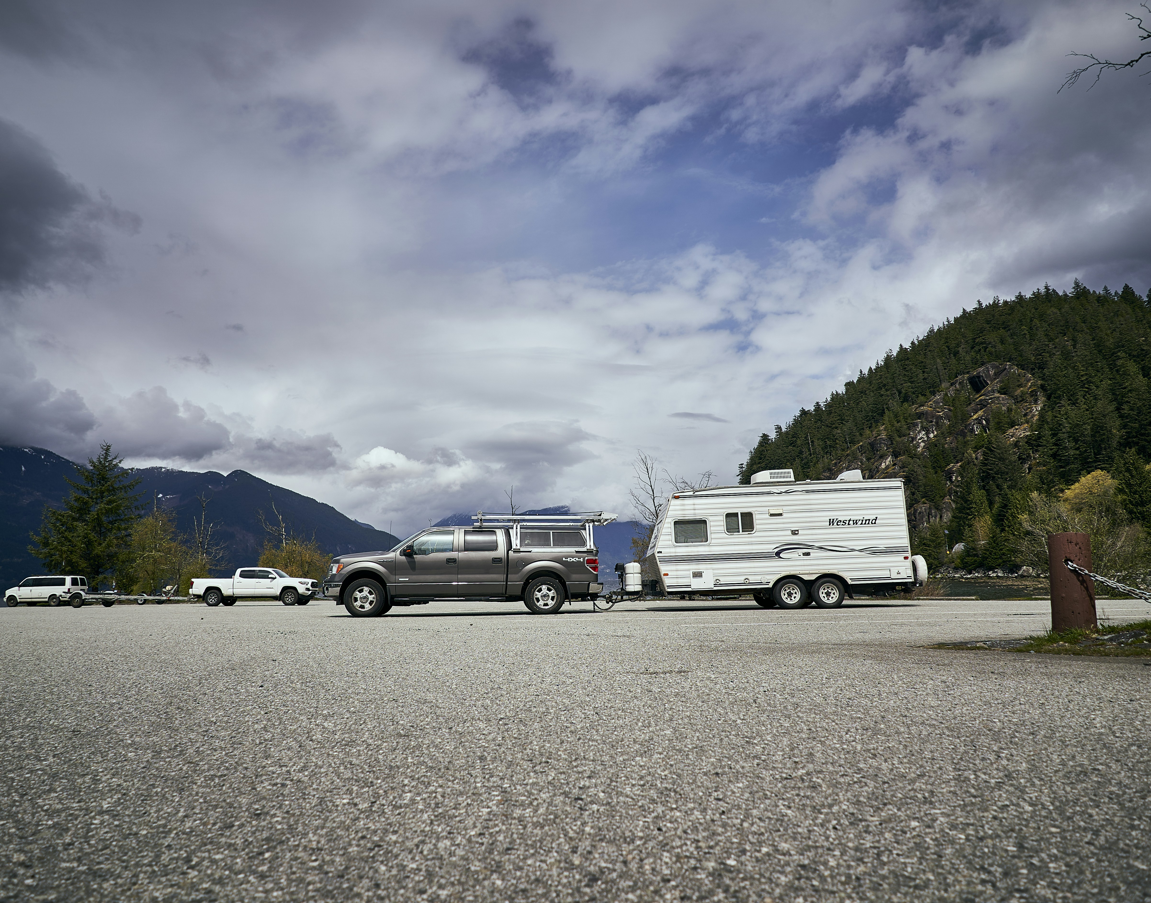 Un groupe de véhicules garés dans un parking avec des montagnes en