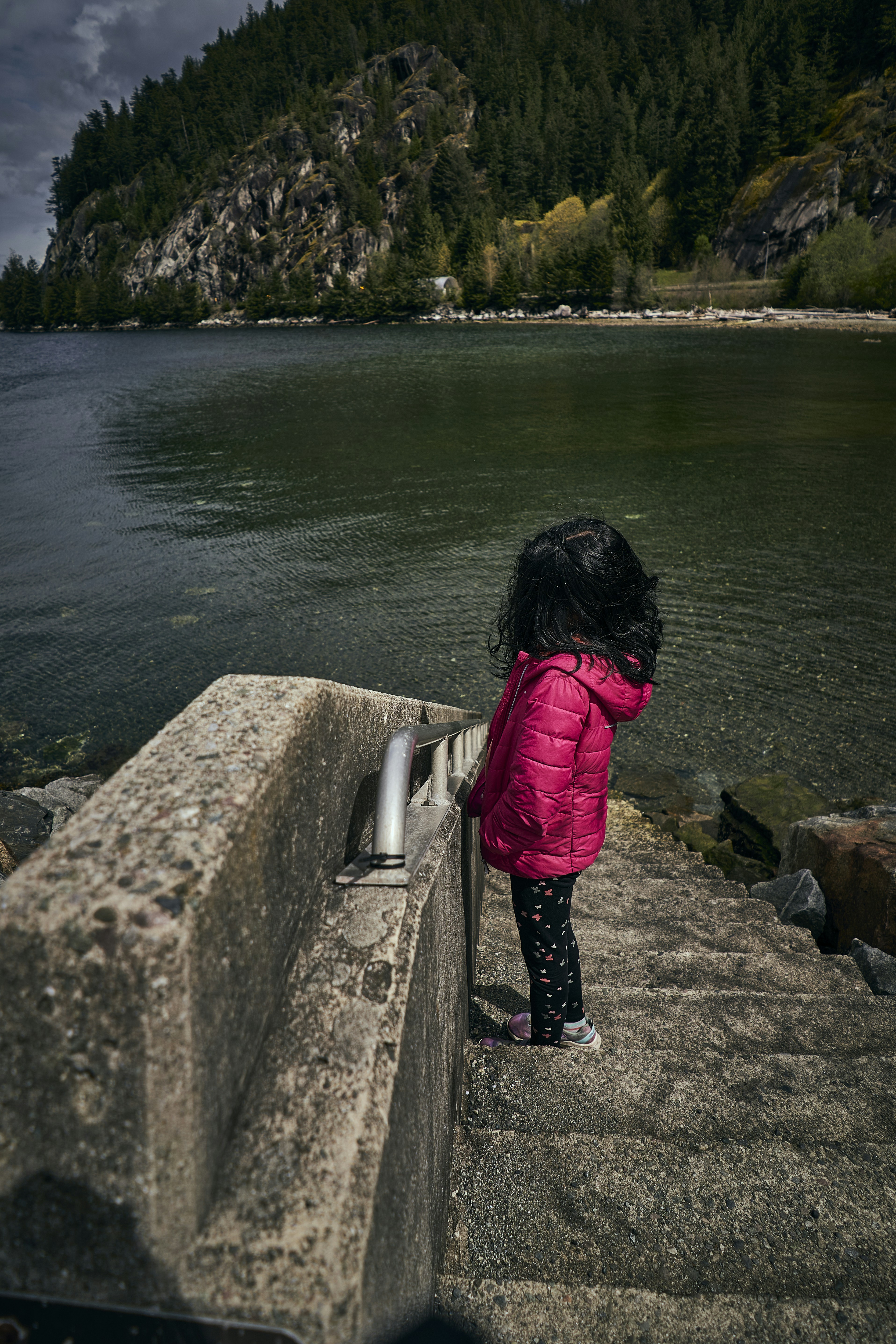 a girl standing on a rock by a body of water