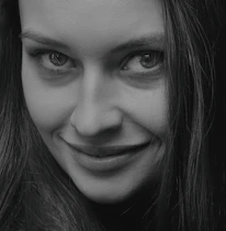 Black and white close-up of the model's expressive eyes and subtle smile.