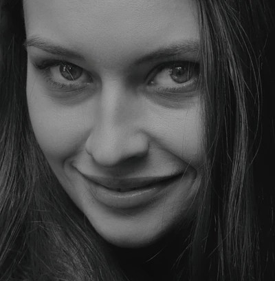 Black and white close-up of the model's expressive eyes and subtle smile.