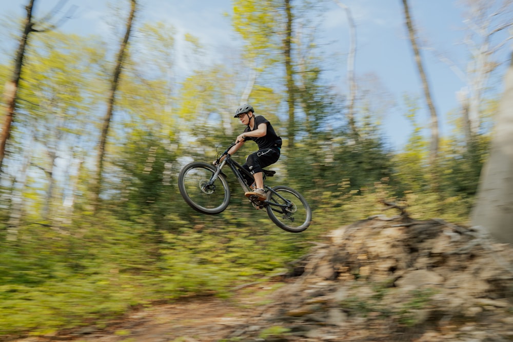 a man riding a bike on a dirt trail in the woods