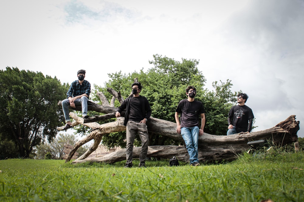 a group of men standing on a log in a grassy area