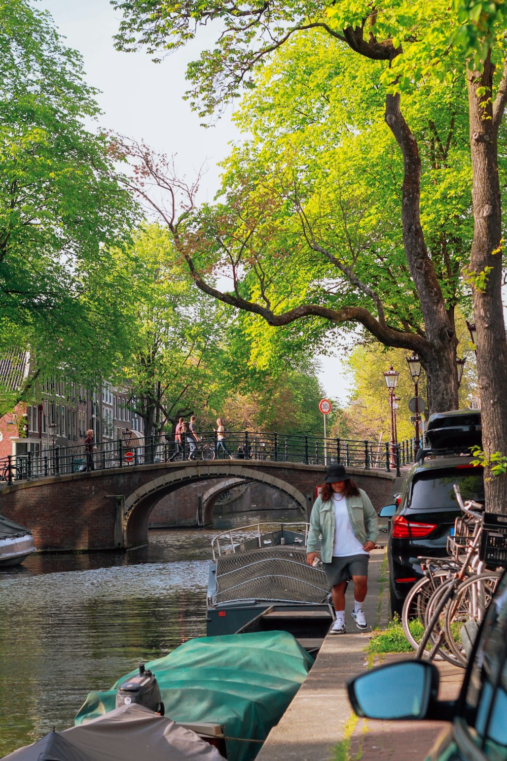 a person walking on a sidewalk next to a river with a bridge