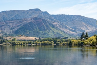 a body of water with trees and a mountain in the background