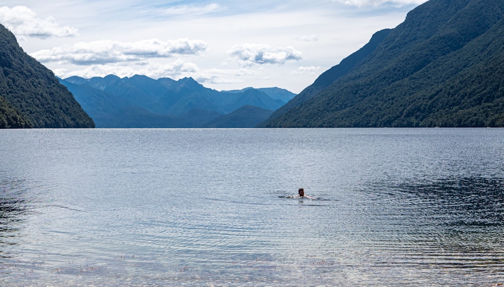 a person in a body of water with mountains in the background with Chilliwack Lake in the background