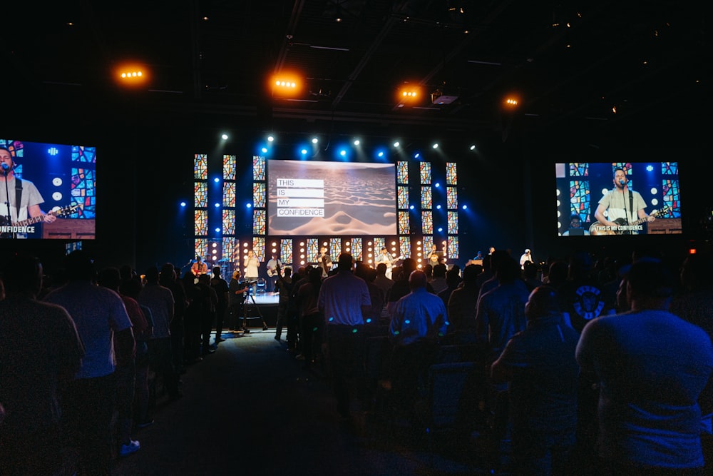 a group of people in front of a stage with screens