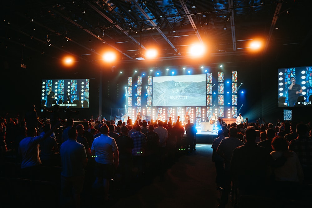a crowd of people in a room with large screens and lights