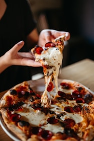 a person takes a slice of pizza