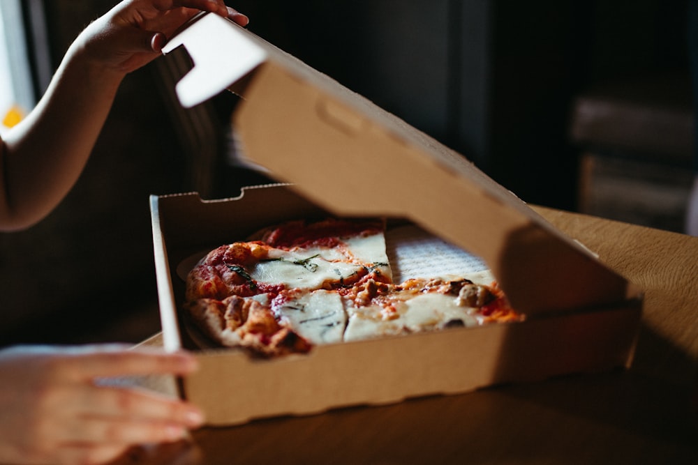 a person holding a slice of pizza