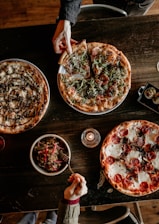 A cozy family gathering around a rustic wooden table with delicious pizzas.