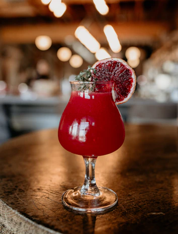 A beautifully styled cocktail with vibrant orange and red hues on a rustic surface